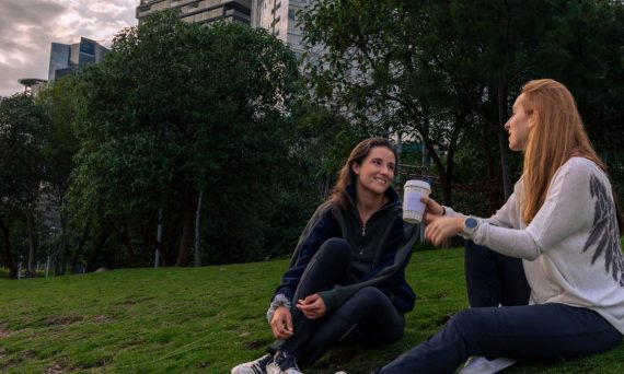 Two women enjoying coffee and conversation in a vibrant park setting in Mexico City.